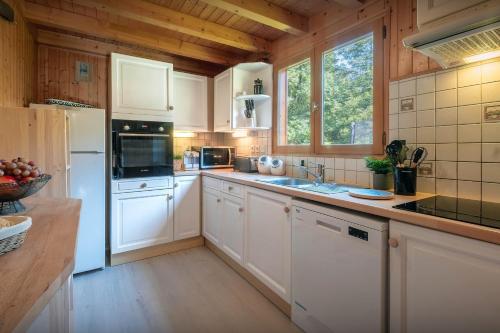 a kitchen with white appliances and a wooden ceiling at Chalet Igel - OVO Network in Châtel