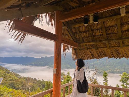 a woman standing in a building looking out at the mountains at Homestay Chân Mây Chiêu Lầu Thi in Hoàng Su Phì