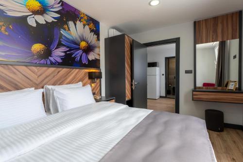 un dormitorio con una cama blanca y una pintura de flores en Yusufhan Suites en Trebisonda