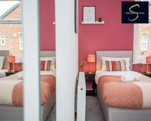 泰恩河畔新堡的住宿－Cosy Business Haven - 3 Bed Newcastle City - FREE PARKING，红色墙壁客房中的两张单人床