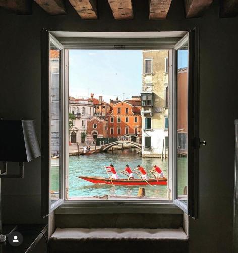 a window with a group of birds in a boat in the water at Palazzetto Pisani Grand Canal in Venice