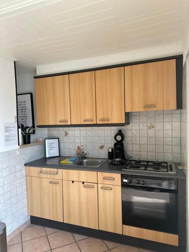 een keuken met houten kasten, een fornuis en een wastafel bij Vakantiewoning Ter Streep in Middelkerke