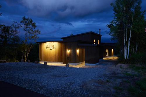 a house with lights on the side of it at night at Rising Sun Furano in Kami-furano
