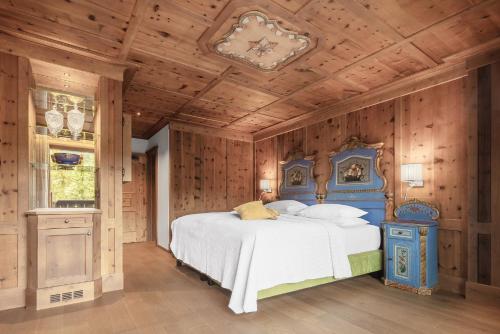 a bedroom with a blue and white bed and wooden walls at Hotel La Perla: The Leading Hotels of the World in Corvara in Badia