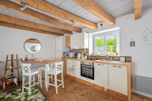 une cuisine avec des armoires blanches et une table et des chaises dans l'établissement Le Cyan - Charmante maison à la campagne, à Limerzel