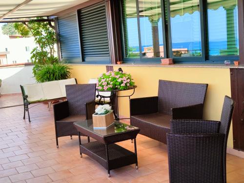 a patio with chairs and a table with flowers on it at "Appartamento del Mare Gliaca" con vista Isole Eolie,ampia terrazza,wifi e parcheggio gratuito in Piraino