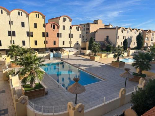 une image d'une piscine en face d'un bâtiment dans l'établissement Les Drom's studio, à Gruissan
