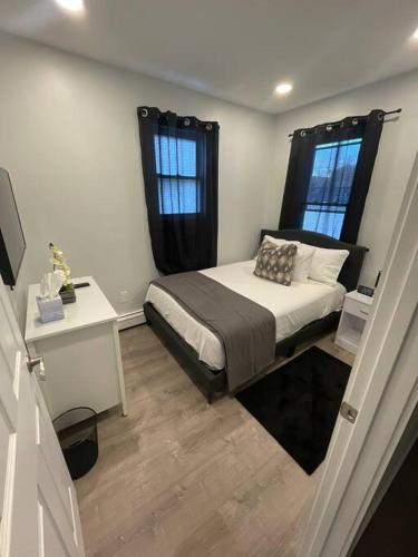 um pequeno quarto com uma cama e 2 janelas em Shirley Air em Boston