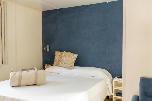 two beds in a room with a blue wall at Gitavillage Talamone in Talamone