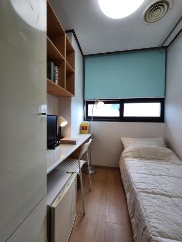 a small bedroom with a bed and a desk at Coem Livingtel in Goyang