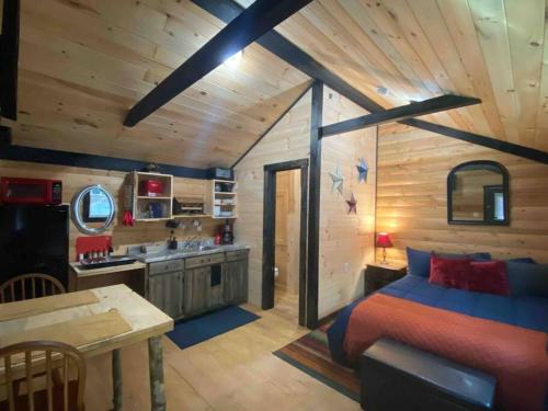 a bedroom with a bed and a kitchen in a cabin at Cozy Log Tiny Cabin in Red River Gorge! in Campton