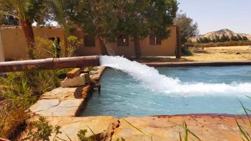 a water pipe spewing water into a swimming pool at White Desert Safari in Bawati