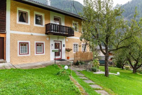 a yellow house with a balcony and a yard at Villa Maria Tirol in Anras