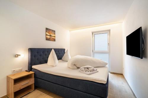 a bedroom with a bed with a blue headboard and a television at Ferienwohnung Lamm 1 in San Valentino alla Muta