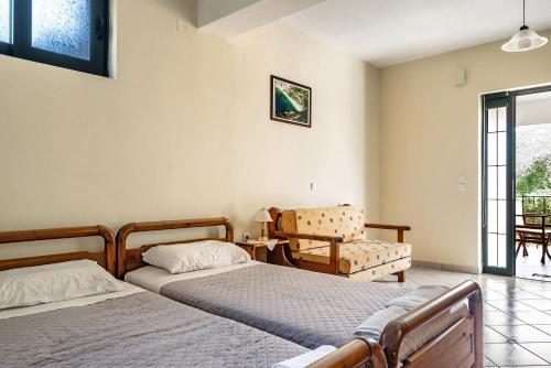 a bedroom with two beds and a chair at Daratos apartment 6 in Kefallonia