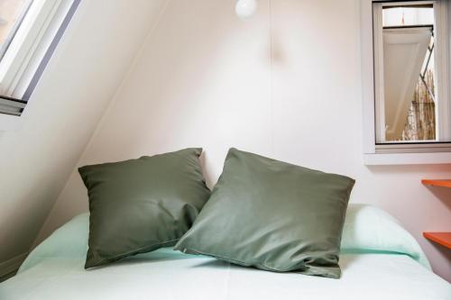 two green pillows sitting on a bed next to a window at Gitavillage Il Gabbiano in Albinia
