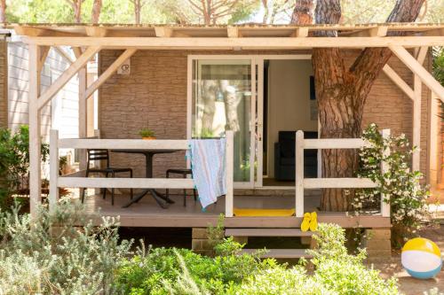 a house with a wooden porch with a table and a tree at Gitavillage Il Gabbiano in Albinia