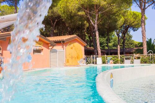 a swimming pool with a water fountain in front of a house at Gitavillage Il Gabbiano in Albinia