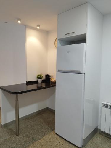 a kitchen with a white refrigerator and a table at Apartament IXA-2 in Manresa