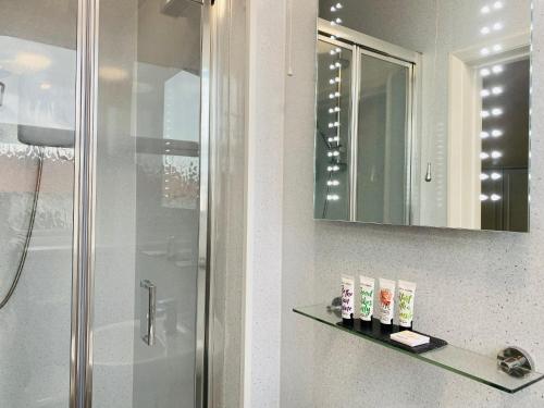 ein Bad mit einer Dusche und einem Spiegel in der Unterkunft Cwtch Guesthouse in Llandudno