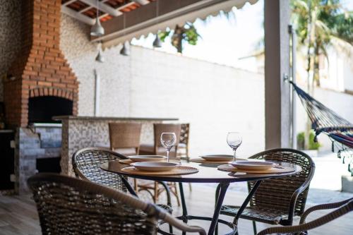 a table with chairs and wine glasses on a patio at Casa em condomínio fechado com piscina in Boracéia