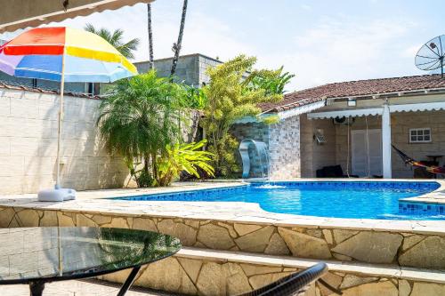 a swimming pool with an umbrella next to a house at Casa em condomínio fechado com piscina in Boracéia