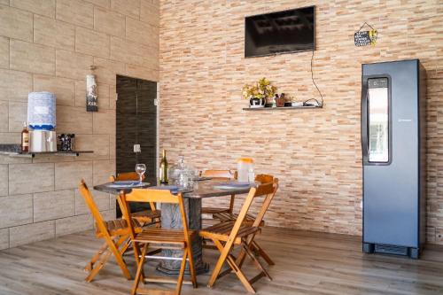a dining room with a table and chairs and a brick wall at Casa em condomínio fechado com piscina in Boracéia