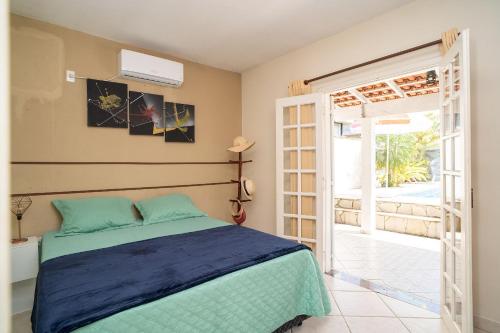 Maravilhosa casa no Cond. fechado Morada da Praia في بوراسيا: غرفة نوم بسرير وباب زجاجي منزلق