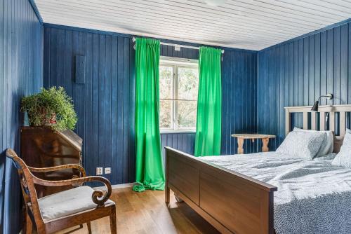 a bedroom with blue walls and green curtains and a bed at Charming holiday home in Kungsgarden, Gastrikland in Kungsgården