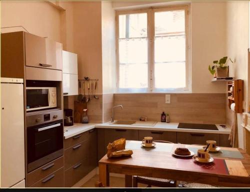 une cuisine avec une table et un four micro-ondes ainsi qu'une fenêtre dans l'établissement La maison des Consuls, à Auxerre