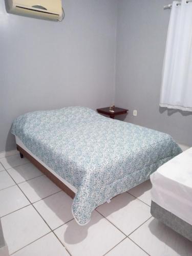 a bedroom with a bed with a blue comforter at Rosa do deserto in Jerônimo Monteiro