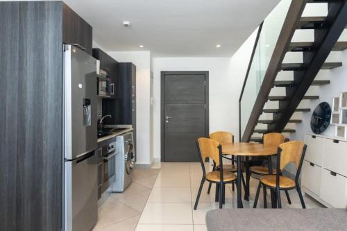 a kitchen with a table and chairs and a staircase at Cosy 1 Bed Loft @Embassy Gardens in Cantonments