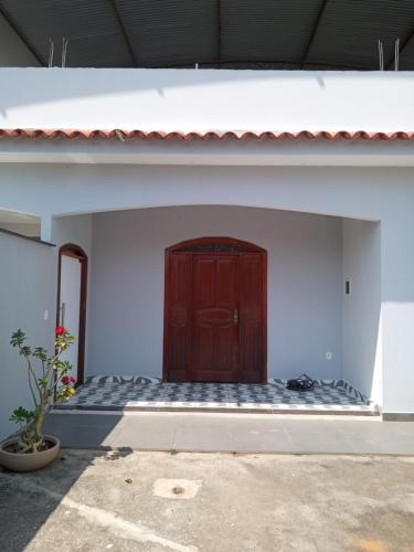 drewniane drzwi w białym budynku w obiekcie Rosa do deserto w mieście Jerônimo Monteiro