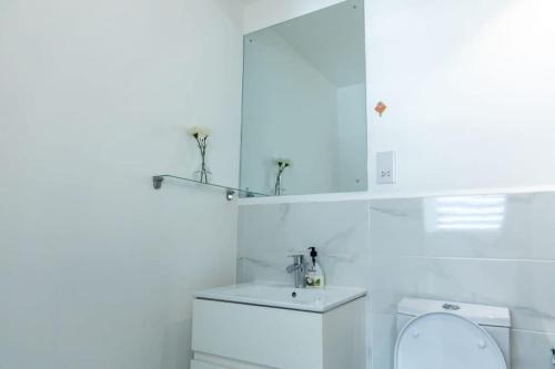 a white bathroom with a sink and a washing machine at Cosy 1 Bed Loft @Embassy Gardens in Cantonments