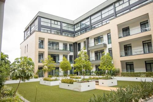 an apartment building with a garden in front of it at Cosy 1 Bed Loft @Embassy Gardens in Cantonments
