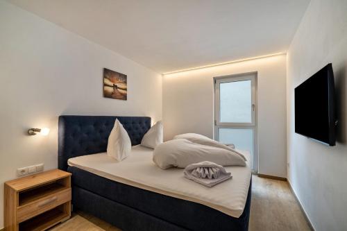 um quarto com uma cama com uma cabeceira azul e uma televisão em Ferienwohnung Lamm 3 em San Valentino alla Muta
