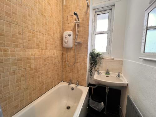 La salle de bains est pourvue d'une baignoire et d'un lavabo. dans l'établissement Rooms in Bethnal Green, à Londres