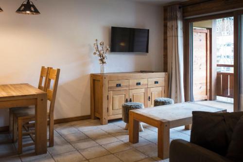 a living room with a table and a tv on the wall at Les Cimes in La Clusaz