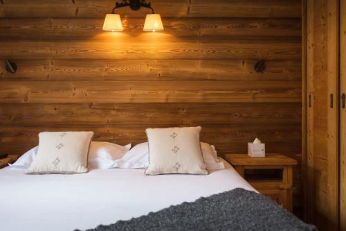 a bed with two pillows in a room with wooden walls at Les Cimes in La Clusaz