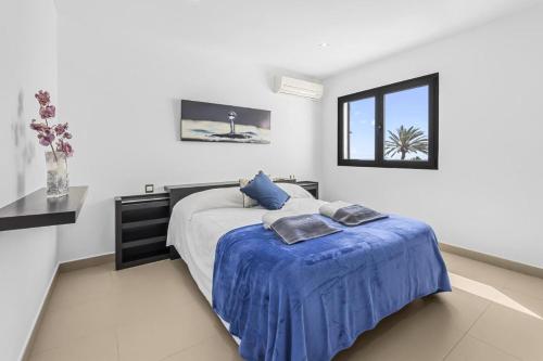 a bedroom with a bed with blue sheets and a window at Casa Airalba in Tías