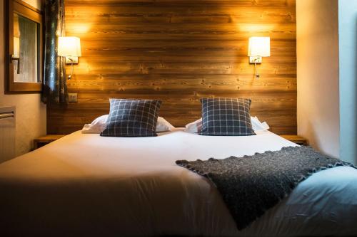 a bedroom with a large bed with a wooden wall at Les Cimes in La Clusaz