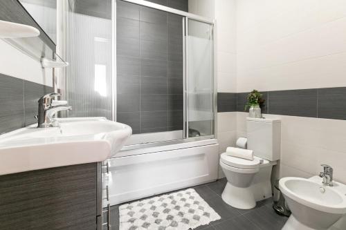 ein Bad mit einem Waschbecken, einem WC und einer Dusche in der Unterkunft Casa Brilhante - Sunny Delight in Nazaré