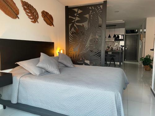 a bedroom with a white bed and a kitchen at Element by Elite, departamento de lujo in Santa Cruz de la Sierra