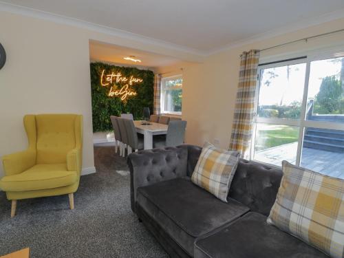 a living room with a couch and a yellow chair at Woodlands Retreat in Ruthin