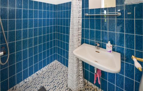 a blue tiled bathroom with a sink and a shower at Awesome Home In Sydals With 2 Bedrooms And Wifi in Vollerup