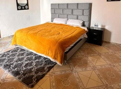 a bedroom with a bed with an orange blanket on it at Hotel Don Quijote in Mineral de Pozos