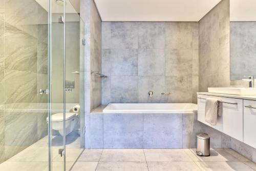a bathroom with a shower and a tub and a toilet at Chelsea on Main in Cape Town