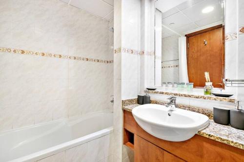 a white bathroom with a sink and a tub and a sink at StoneTree - 1BR apartment with Lake View in Dubai