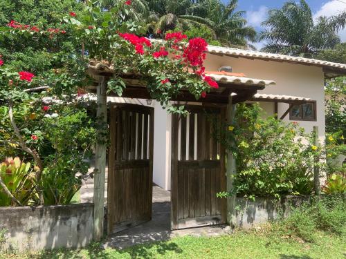 una entrada a una casa con flores rojas en Casa dos Paulistas - Ilha de Boipeba, en Isla de Boipeba