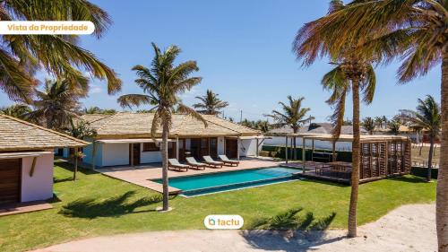 a villa with a swimming pool and palm trees at Casa Mutana Fortim Frente Mar Kiteplace de Luxo in Maceio